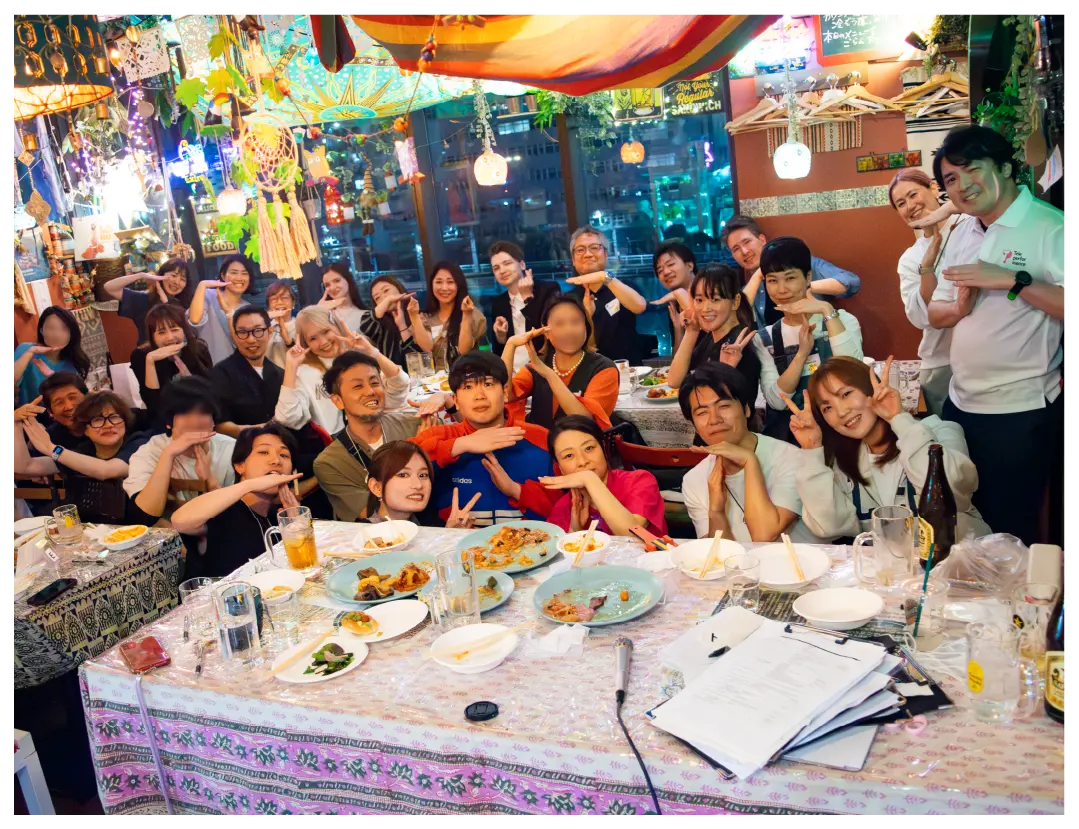 A large group poses playfully together at a lively restaurant party.
