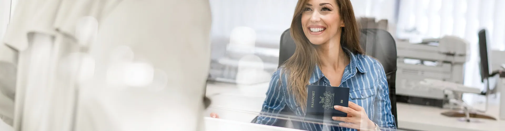 Woman holding a passport while speaking with a consular services agent.