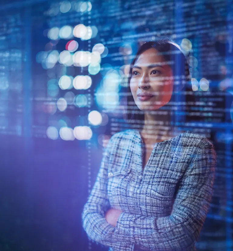 Asian professional working in a high-tech environment with digital code displayed on a screen.